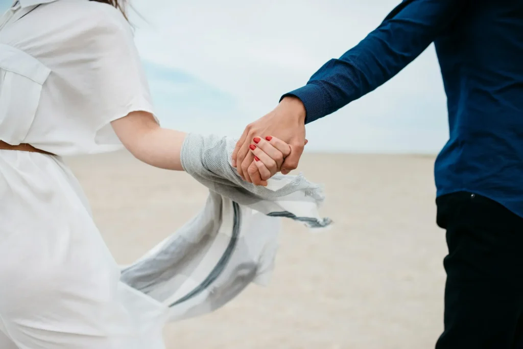 Esposos agarrados de la mano en la playa